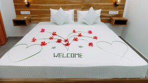 Ein ordentlich bezogenes Bett mit weißer Bettdecke, einem Holz-Kopfteil und einem 'WELCOME'-Schild.