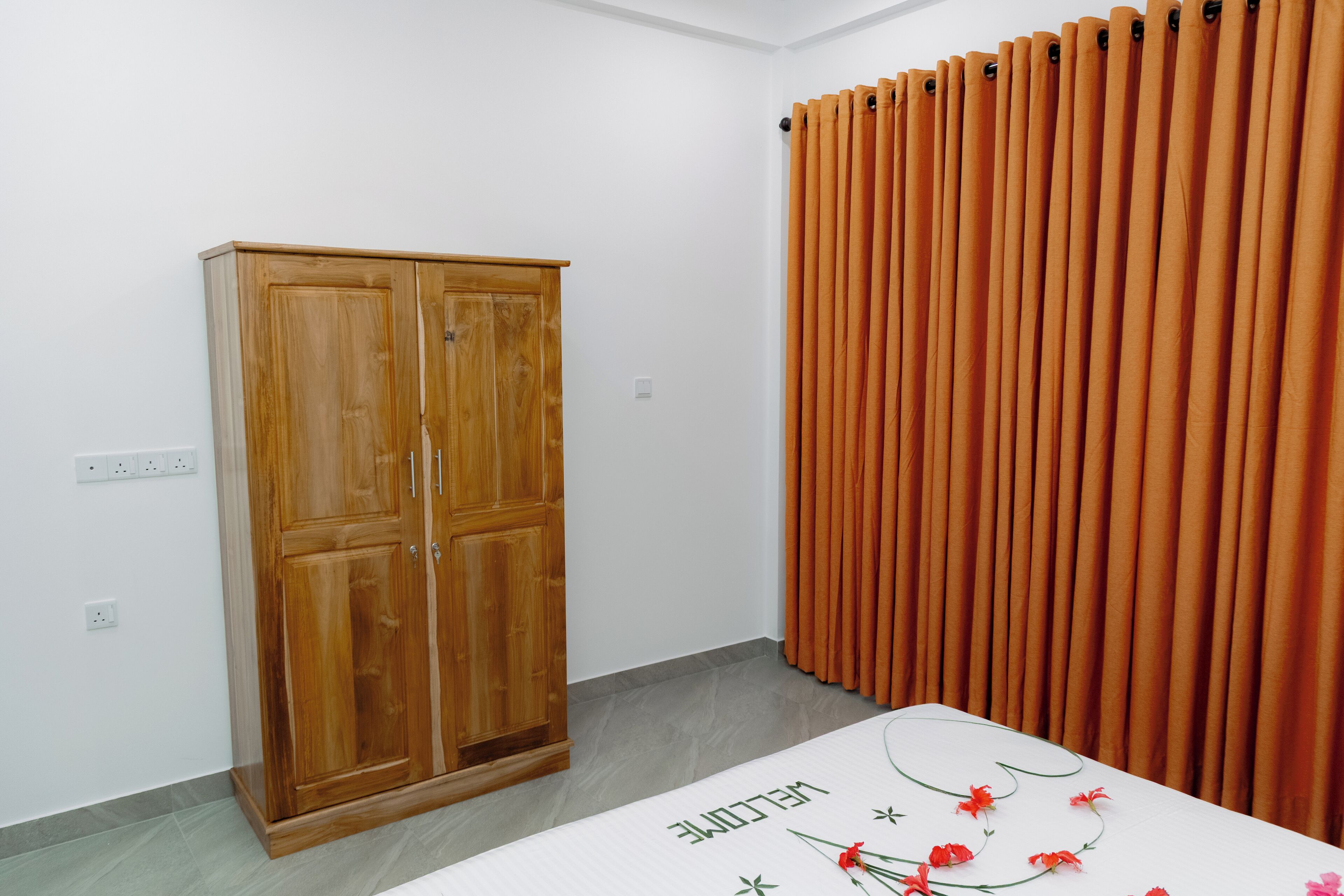 Ein Zimmer mit einem Holzschrank, einem Vorhang und einem Bett mit Fußmatte.
