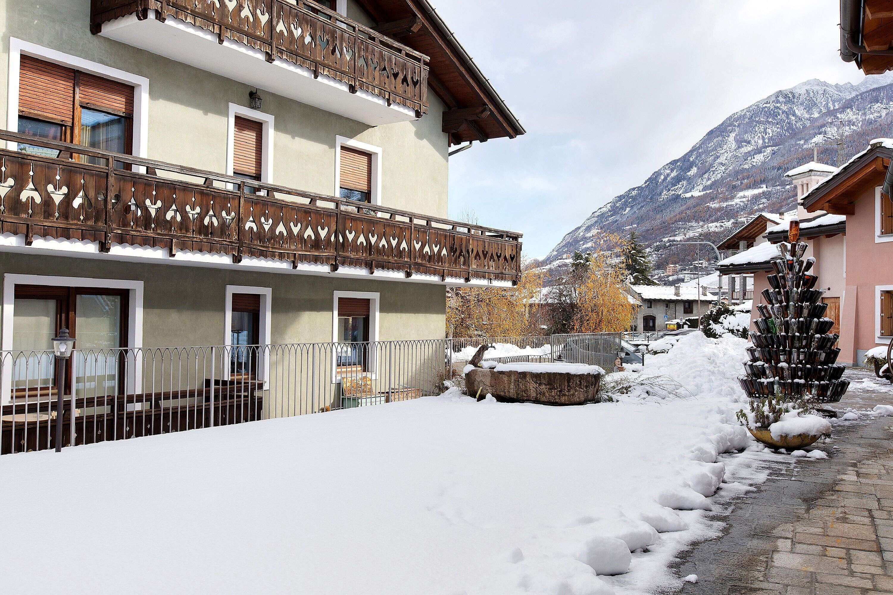 Un immeuble à plusieurs étages doté de balcons, un sol recouvert de neige et une montagne en arrière-plan.