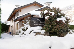 A building with a sign reading 'Au Petit Chevrolet Apartments' surrounded by snow.