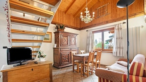 Un intérieur en bois comprenant une télévision, un meuble en bois, une table à manger, des chaises et un canapé.