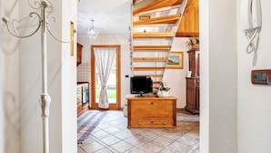 Un escalier menant à un deuxième étage, une armoire en bois avec un téléviseur et un téléphone fixé au mur.