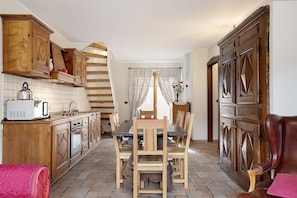 A kitchen with wooden cabinets, a dining table, and chairs.