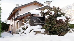Un edificio con un letrero que dice 'Au Petit Chevrolet Apartments' rodeado de nieve.
