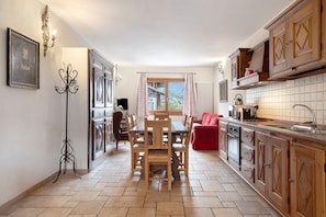 A kitchen with wooden cabinets, a dining table, and a view of the outdoors.