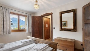 Un dormitorio con cama y cómoda de madera, un espejo y una ventana con cortinas.