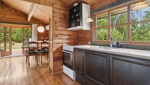 A wooden cabin interior with a kitchen, dining area, and large windows. - 4 Star Holiday Home in Glesborg (Glesborg)