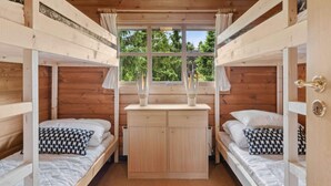 A cabin with two bunk beds, a wooden wardrobe, and a window with a view of trees. - 4 Star Holiday Home in Glesborg (Glesborg)