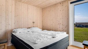 A bedroom with a bed, a chair, and a large window.