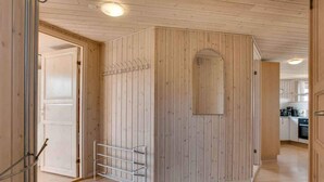 A room with wooden panel walls, a metal rack, and a door leading to a kitchen area.