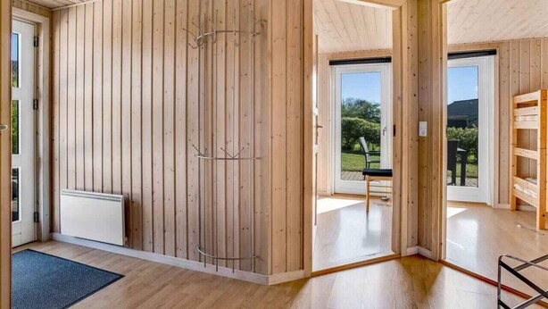 A spacious room with wooden walls and a large sliding door leading to an outdoor area.