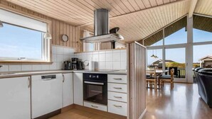A modern kitchen with white cabinets, a stove, and a large window.