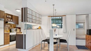 A modern kitchen with a dining area, wooden cabinets, and a built-in microwave. - 5 Star Holiday Home in Saltum (Saltum)