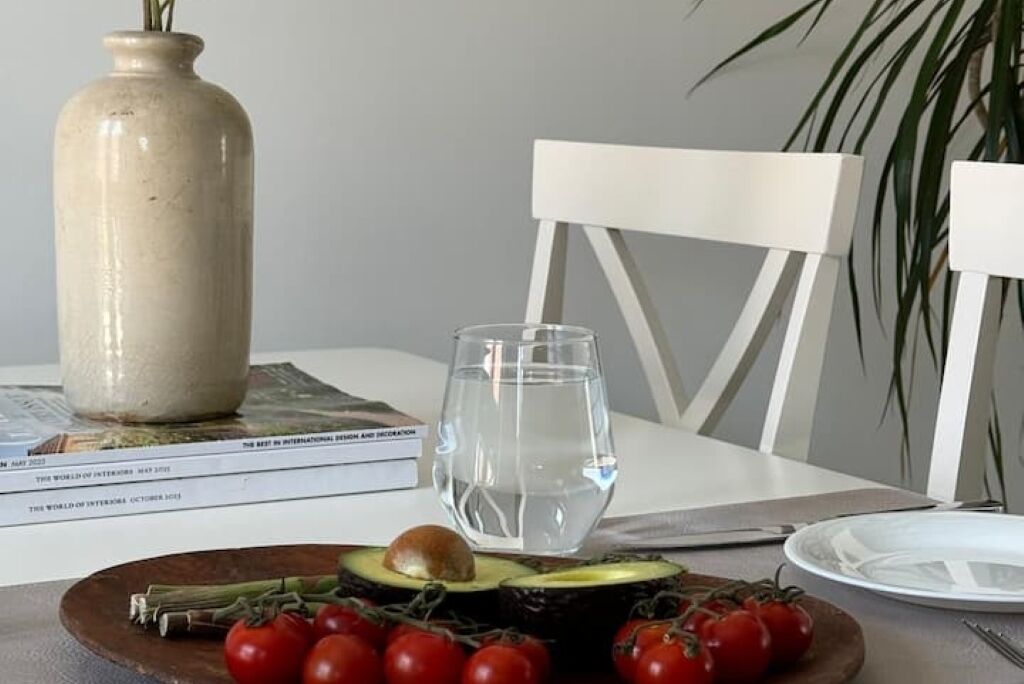 A dining table with a plate of food, a glass of water, and a vase.