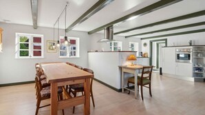 Une cuisine spacieuse avec un îlot central, une table à manger en bois et des chaises.