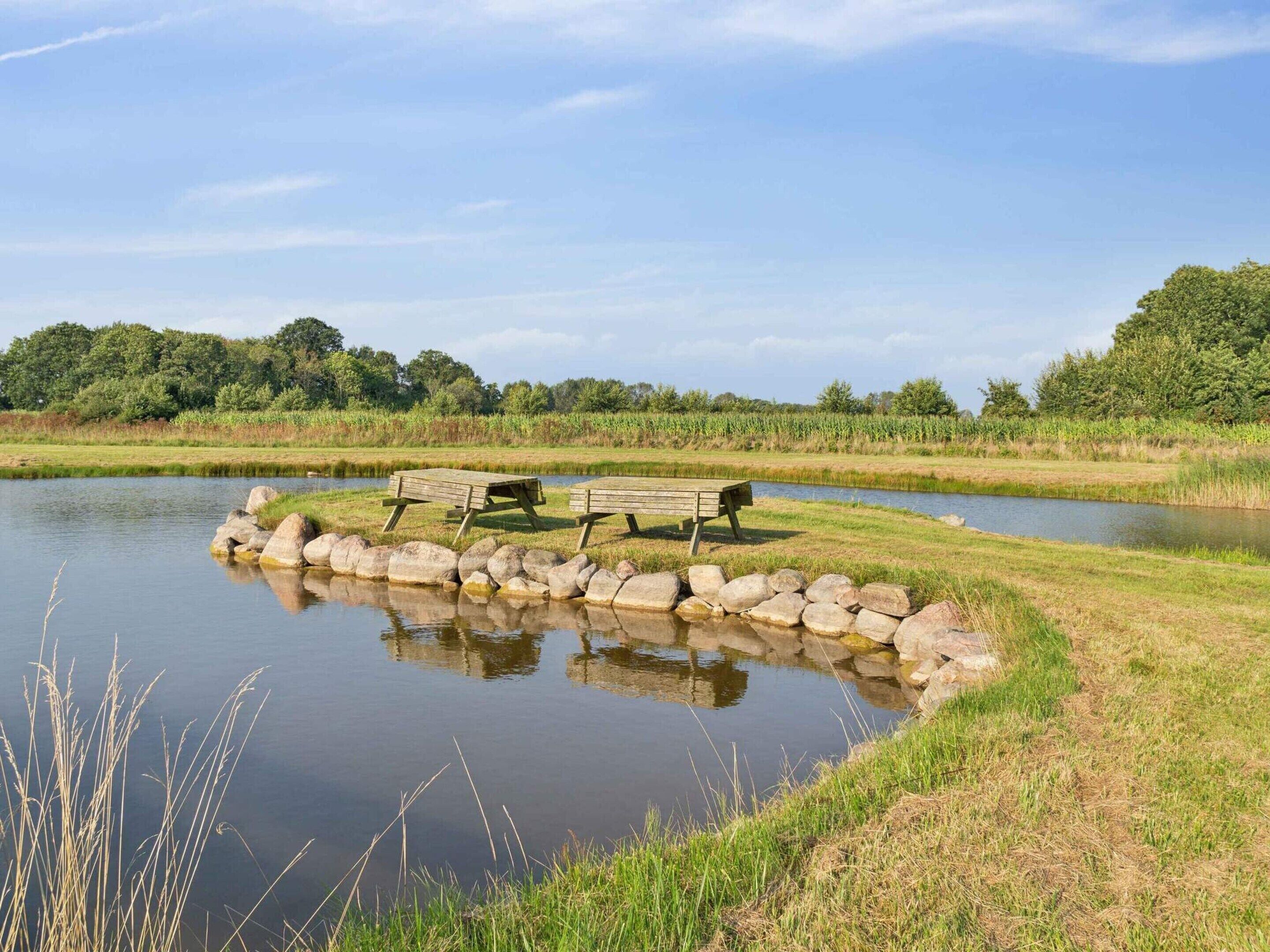 A tranquil lakeside setting with a wooden bench and a stone wall.