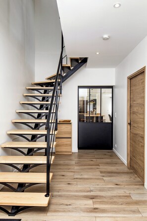 Una moderna scala con gradini in legno e ringhiere in metallo nero che conduce a un piano superiore.