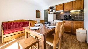 A compact kitchen with wooden cabinets, a microwave, and a coffee maker. - Apartments for 6 People (Albiez-Montrond)