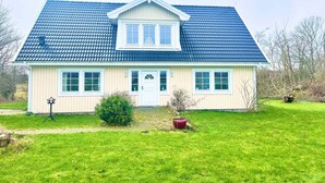 A two-story house with a blue roof, a front door, and a small front yard with a potted plant and a street lamp. - 5 Star Holiday Home in Faxe Ladeplads (Faxe Ladeplads)