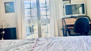 A bedroom with a bed, a desk with a computer monitor, and a window with curtains. - 5 Star Holiday Home in Faxe Ladeplads (Faxe Ladeplads)