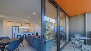 A modern kitchen with a dining area, a sofa, and a balcony with outdoor seating. - Cityside Comfort!  Modern 2BR, 2BA with Parking (Christchurch)