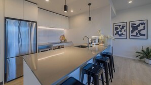 A modern kitchen with a large island, stainless steel appliances, pendant lighting, and a minimalist design. - Cityside Comfort!  Modern 2BR, 2BA with Parking (Christchurch)