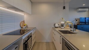 Een moderne keuken met een inbouwoven, een spoelbak en een aanrecht met een waterkoker en een koffiezetapparaat.