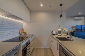 Eine moderne Küche mit Backofen, Spüle und einer Arbeitsplatte mit Wasserkocher und Kaffeemaschine.