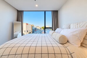 A hotel room with a large bed, a view of the city, and a modern design. - Tuam City Side Stay | 2BR + 2BA + Parking (Christchurch)