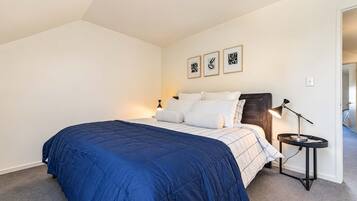 A bedroom with a bed, a nightstand, a lamp, and three framed pictures on the wall.