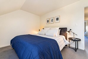 Une chambre à coucher avec un lit, une table de chevet, une lampe et trois tableaux encadrés accrochés au mur.