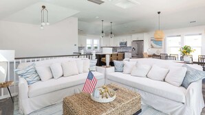 A spacious living room with a white sofa, a coffee table with an American flag, and a ceiling fan. - New Listing! Pool, Hot Tub & Game Room! (Corolla)
