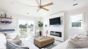 A spacious living room with a ceiling fan, a fireplace, a TV, and a balcony with outdoor furniture. - New Listing! Pool, Hot Tub & Game Room! (Corolla)