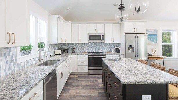 A modern kitchen with white cabinets, granite countertops, stainless steel appliances, and a large island. - New Listing! Pool, Hot Tub & Game Room! (Corolla)