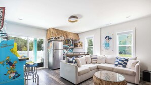 A modern kitchen with a built-in refrigerator, a blue bar stool, and a white sofa with blue cushions. - New Listing! Pool, Hot Tub & Game Room! (Corolla)