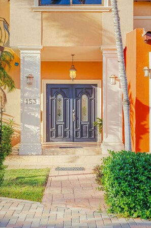 Un bâtiment avec une porte bleu foncé, le numéro « 153 » sur le côté gauche et un luminaire au-dessus de la porte.