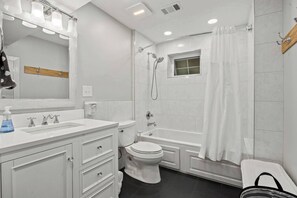 Une salle de bain moderne avec un meuble-lavabo blanc, des toilettes, une baignoire et une douche.