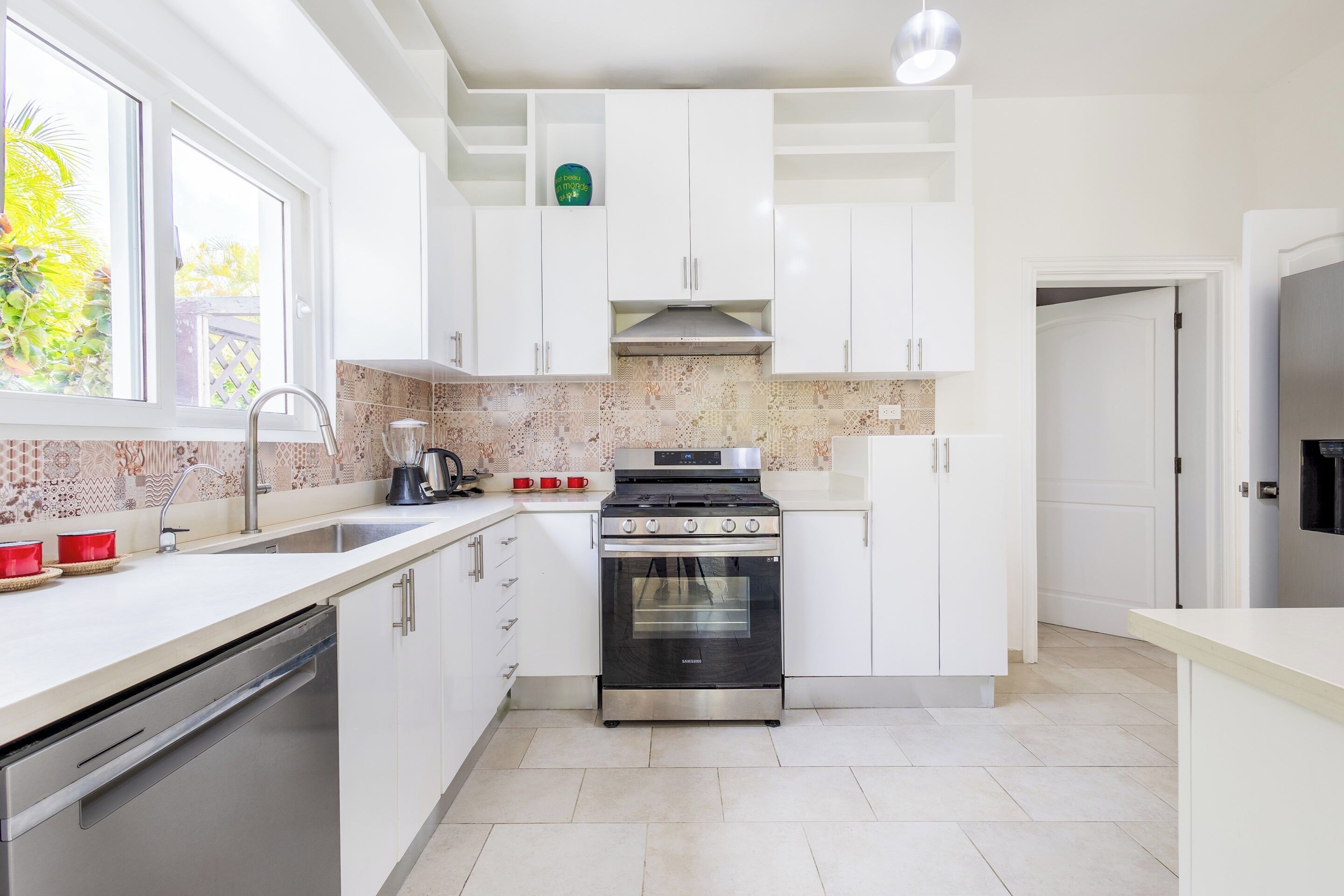 A modern kitchen with white cabinets, a stainless steel oven, and a tiled backsplash.