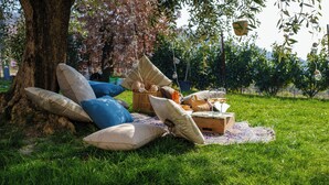Ein Picknick unter einem Baum mit Kissen, einem Korb und einer Decke.
