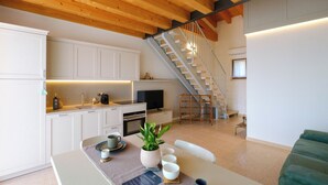Eine moderne Küche mit weißen Schränken, einem Esstisch mit einer Pflanze als Mittelpunkt und einer Treppe, die zu einer oberen Ebene führt.