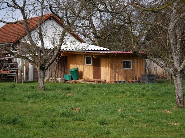 A wooden cabin with a red roof, a front porch, and a stack of firewood. - Holiday Apartment 'Obere Alm' with Shared Garden, Balcony, and Wi-Fi (Oberkirch)