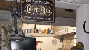 Een kitchenette met een bordje voor een koffiebar, een koffieapparaat en een koelkast met een koffieontwerp.