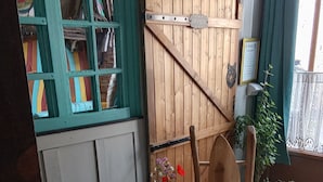 Een gezellige kamer met een groene bank, een klein rond tafeltje met een bloevas, een houten stoel en een vloer met patroon.