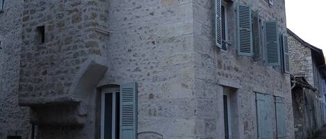 Ein Gebäude aus Stein mit vielen Fenstern und Fensterläden.