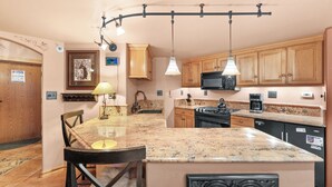A kitchen with granite countertops, wooden cabinets, a black refrigerator, and a microwave.
