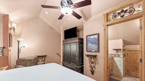 A bedroom with a bed, a ceiling fan, a wardrobe, a television, and a bathroom with a shower and a tiled wall. - Luxury European-Style Penthouse at Copper Mountain (Frisco)