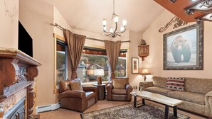 A cozy living room with a fireplace, leather armchairs, a sofa, and a large bear picture on the wall.
