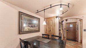A dining area with a wooden table and chairs, a framed picture on the wall, and a hanging light fixture. - Luxury European-Style Penthouse at Copper Mountain (Frisco)