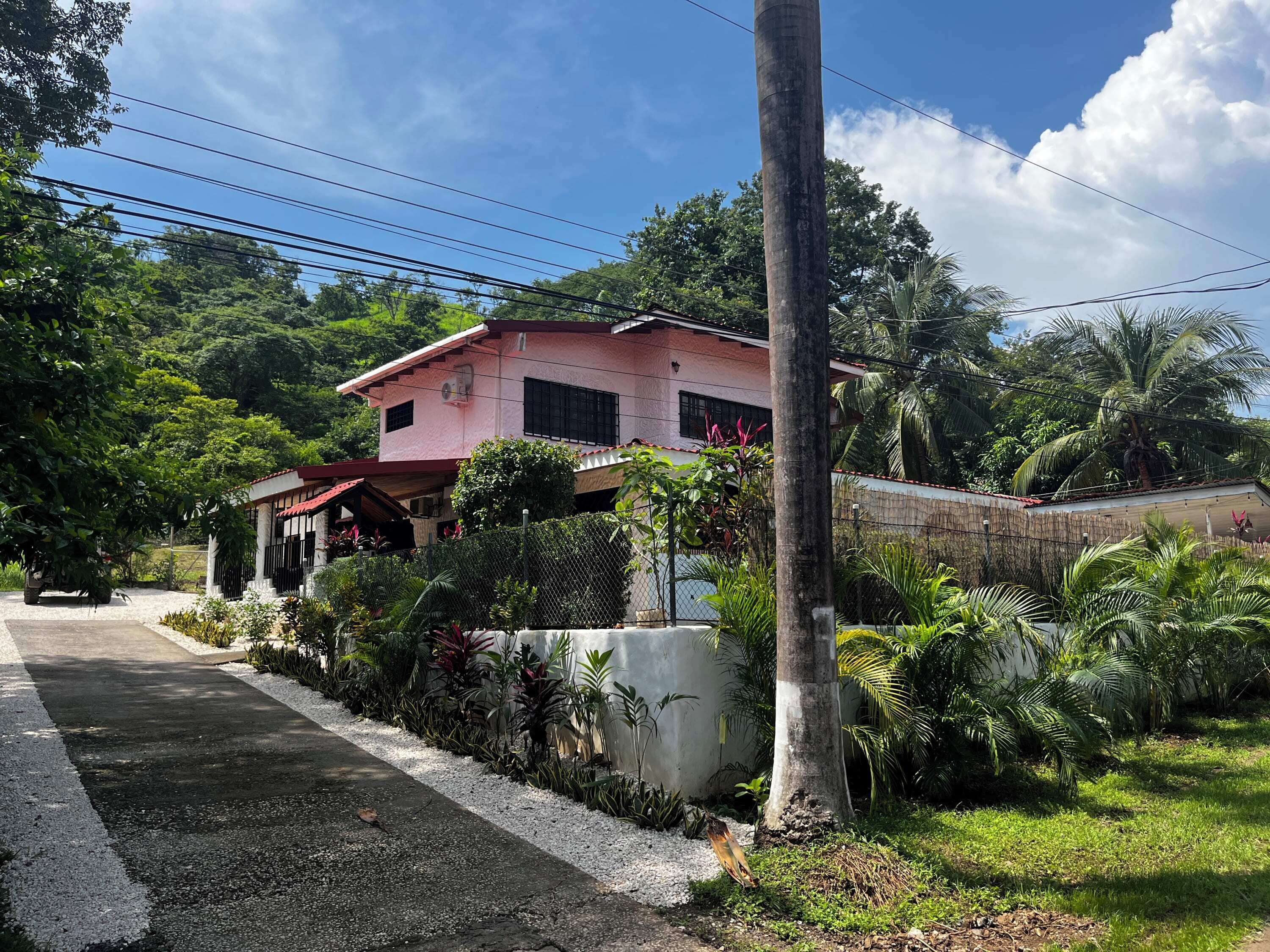A pink house with a garden and a fence.