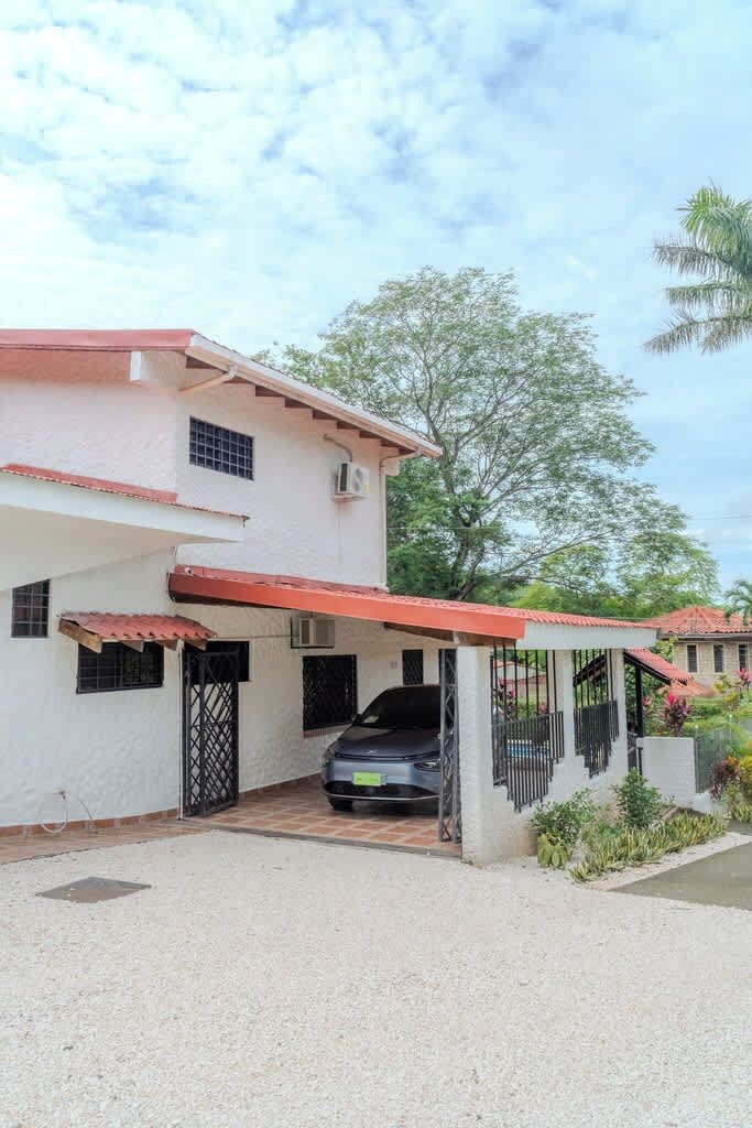 A two-story house with a covered driveway and a car parked inside.